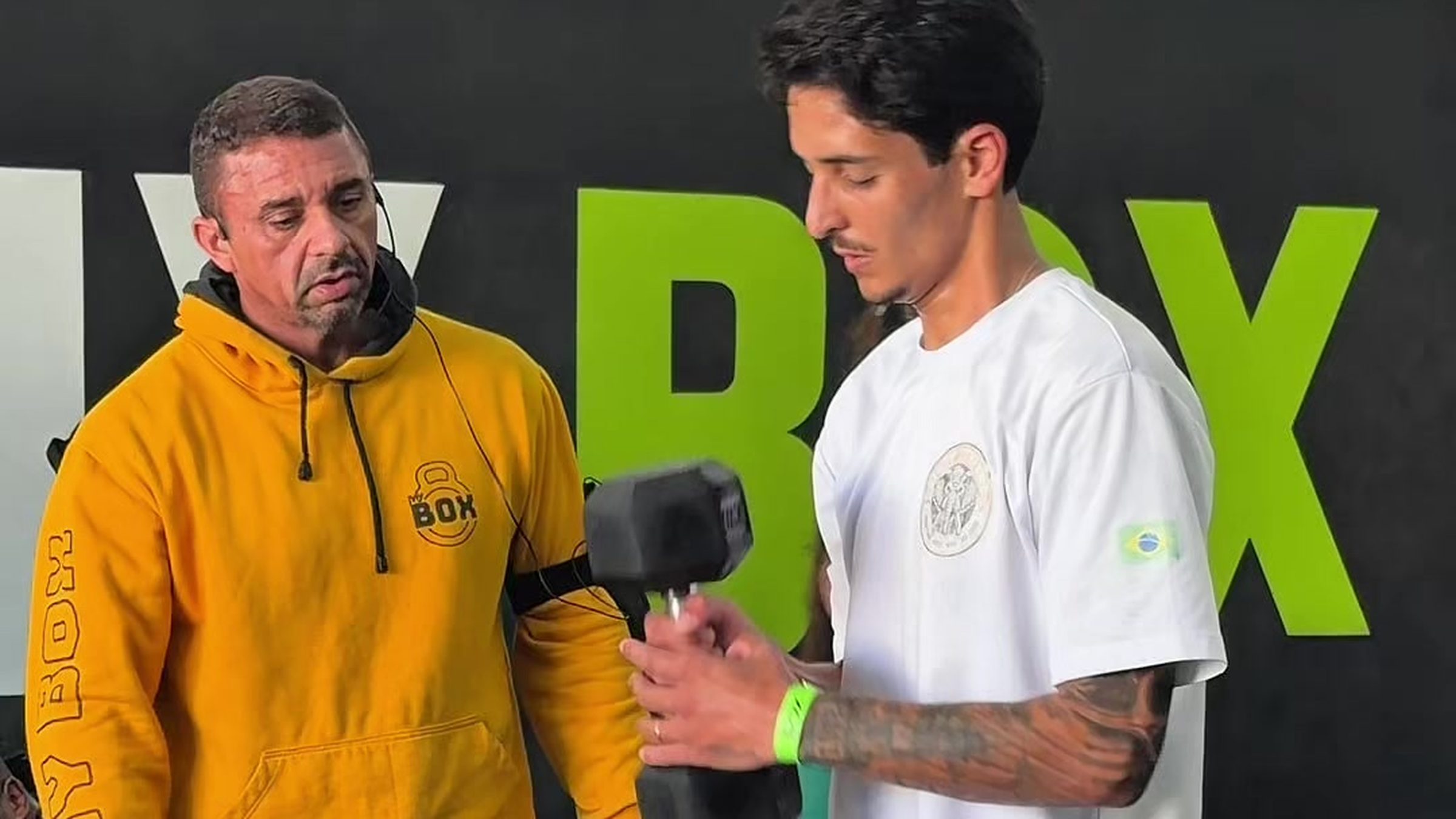 Sabóia, de moletom amarelo, ao lado de um aluno com halter na mão dentro do box do MyBox São Roque