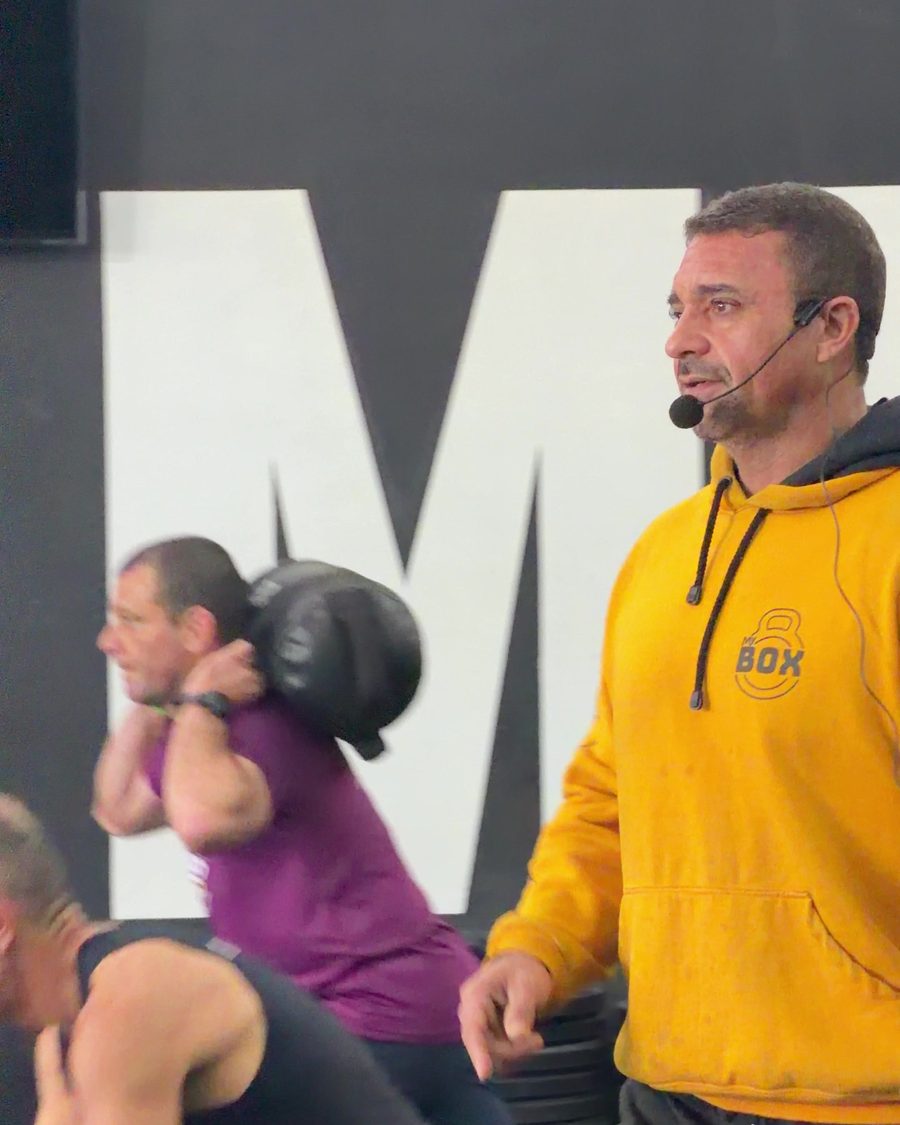 Sabóia, dono e treinador do MyBox São Roque, de moletom amarelo e headset, comandando a aula